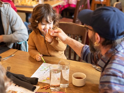 a man feeding a child at a table