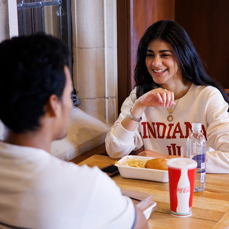 a woman smiling at a man sitting at a table with food