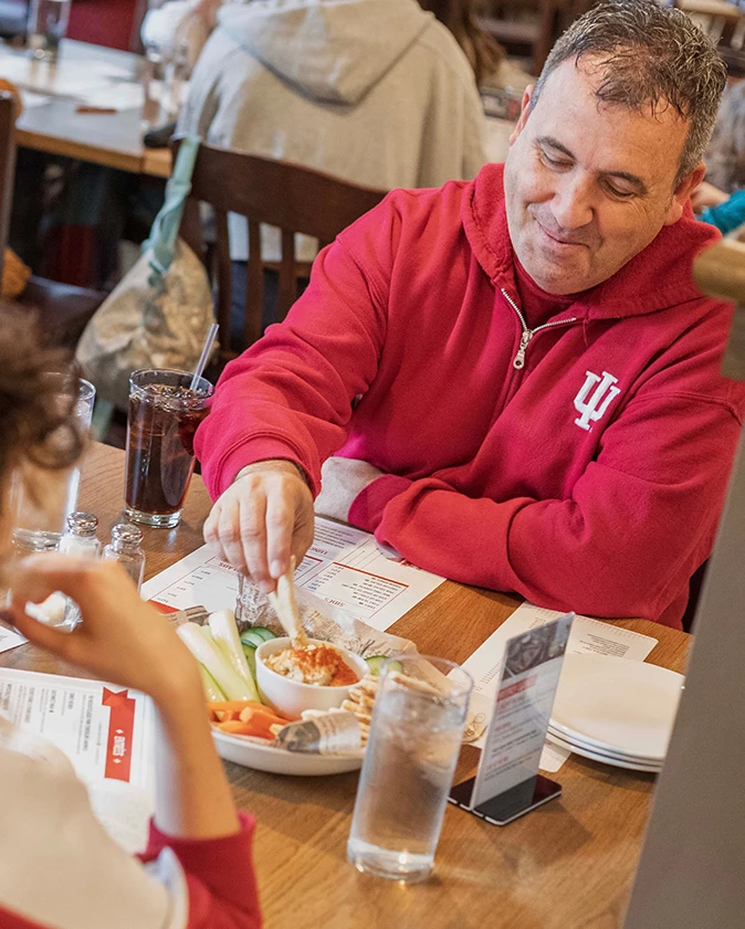 a man in a red sweatshirt eating at a table