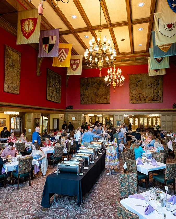 a group of people sitting at tables in a room with flags