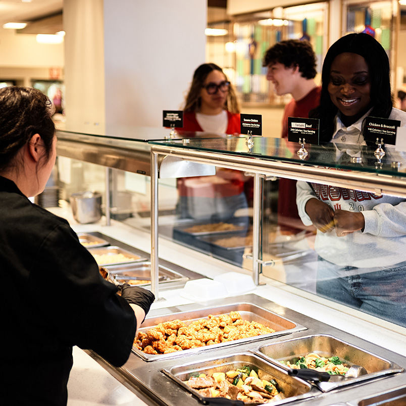 a woman serving food in a buffet