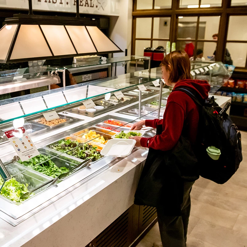 a woman standing at a counter with food in it