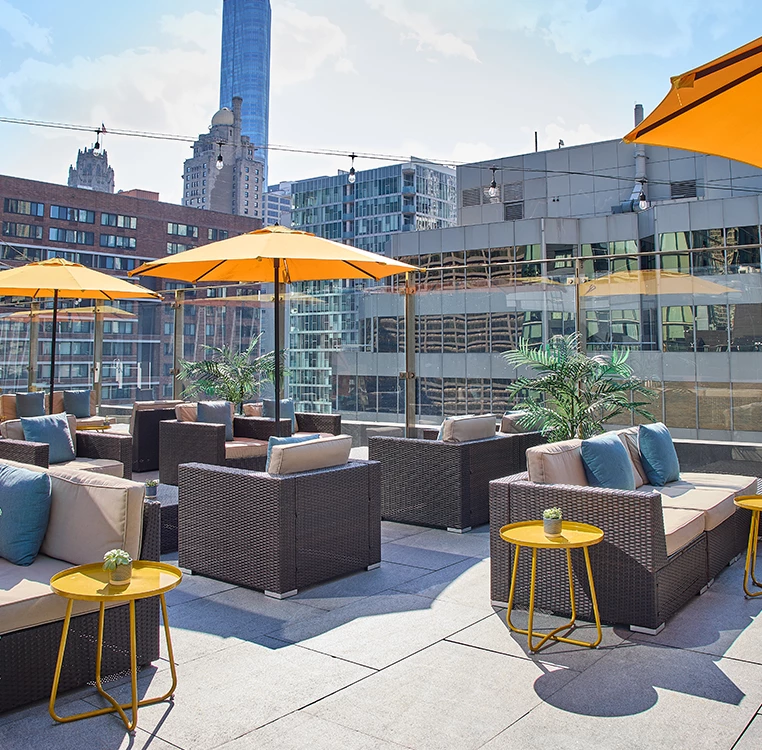 A rooftop patio with outdoor seating and umbrellas overlooking the city.