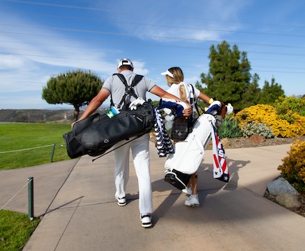 a man and woman carrying golf clubs