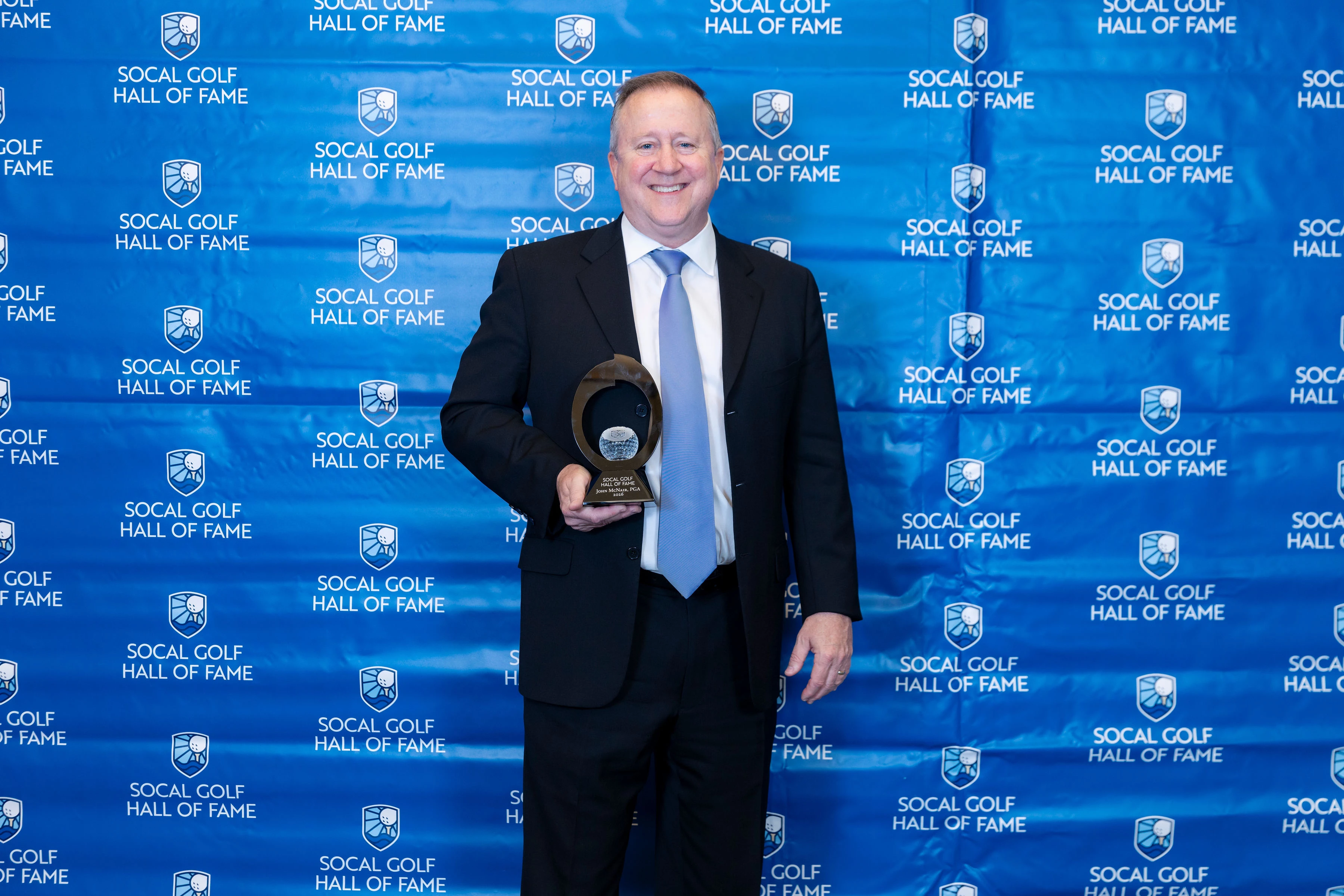 a man in a suit holding a trophy