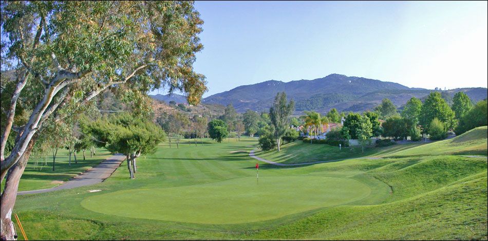 a golf course with trees and mountains in the background