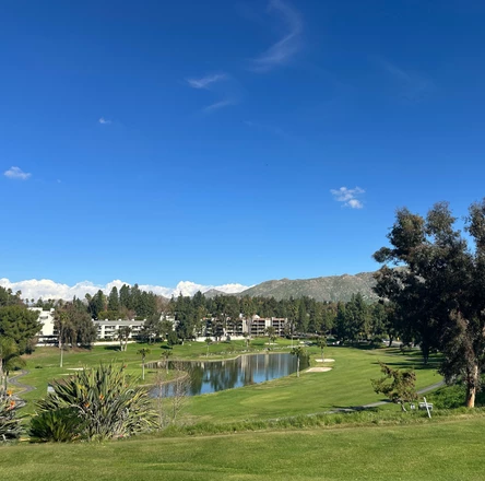 a golf course with a pond and buildings in the background