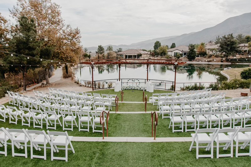 a wedding venue with white chairs and a lake
