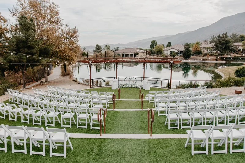 a wedding venue with white chairs and a lake