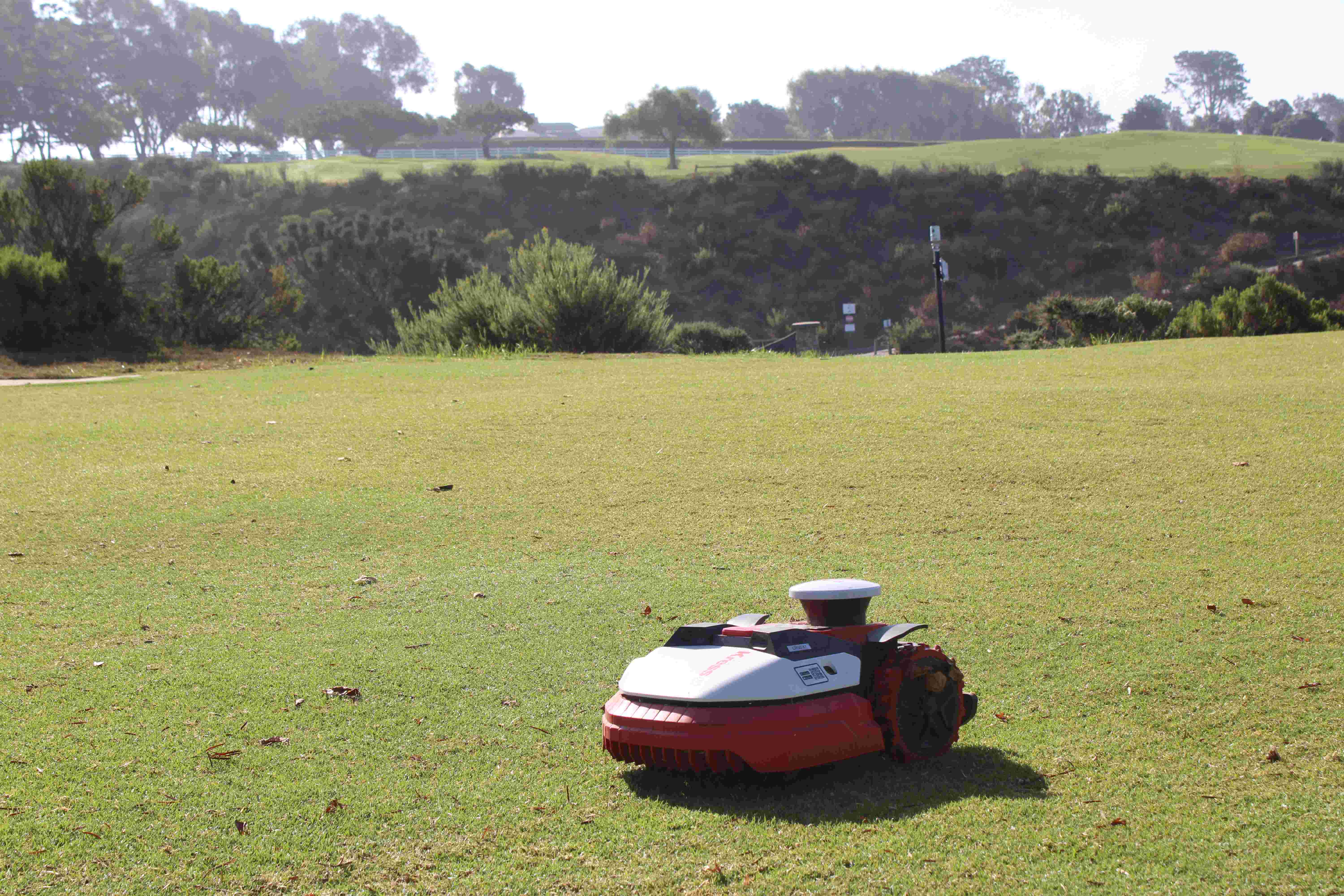 a red and white robot on a green field