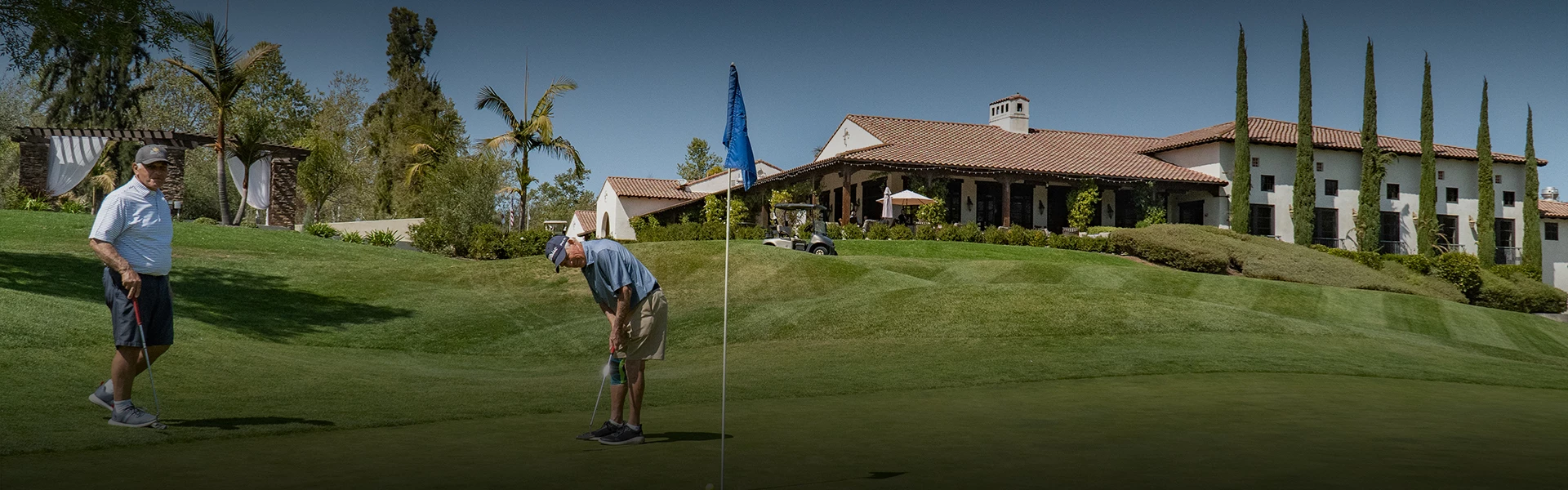 two men wearing blue collared shirts while golfing on the course