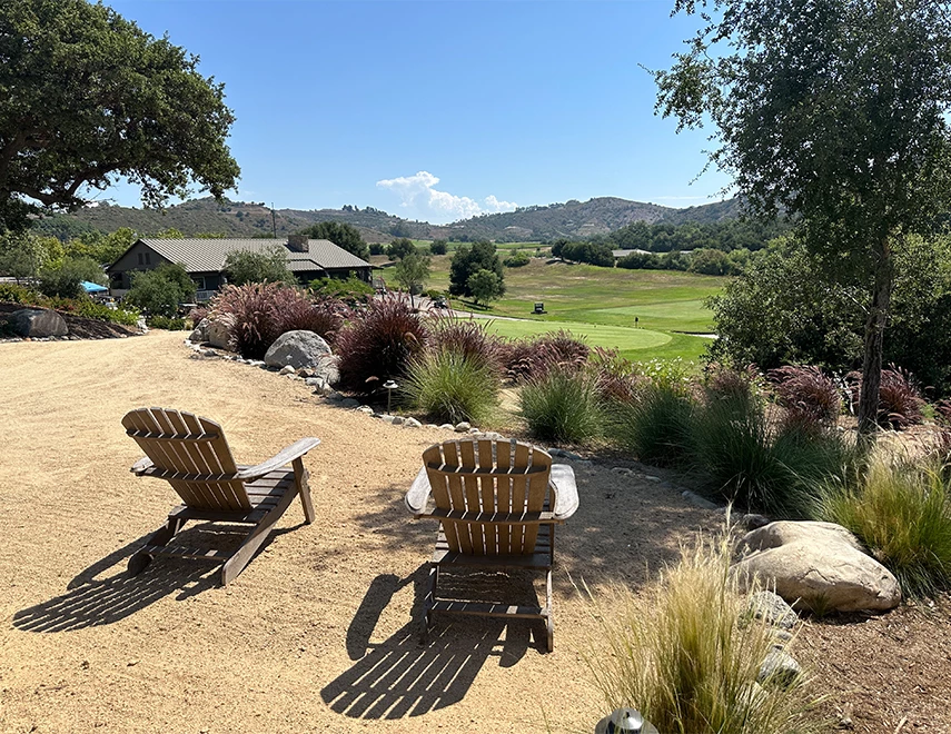 chairs on a dirt path with grass and trees