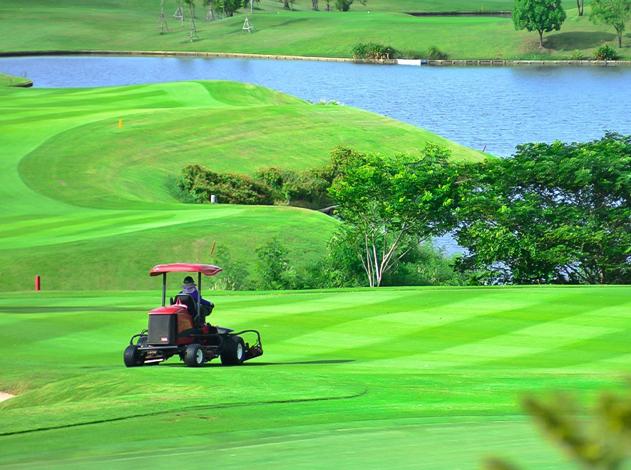 a person riding a lawn mower on a golf course