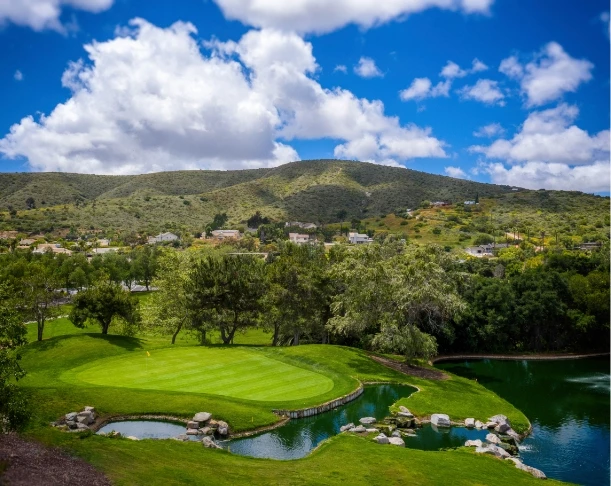 a golf course with a lake and a hill in the background