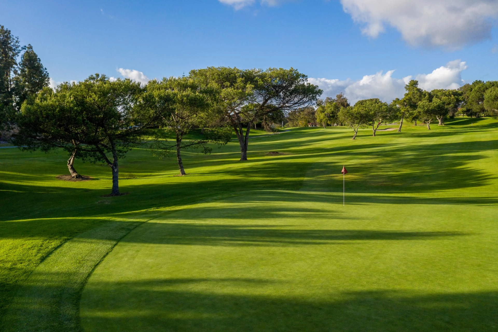 a golf course with trees and blue sky