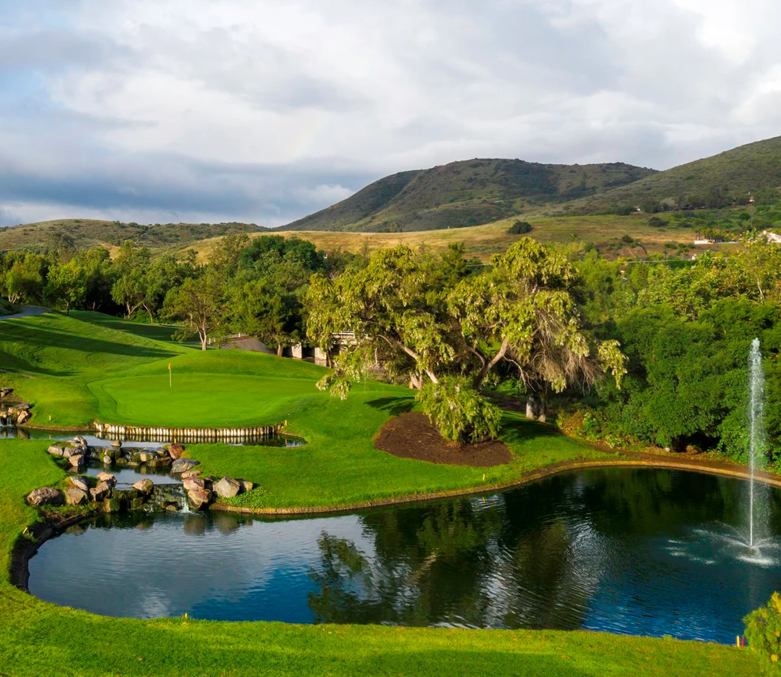 a golf course with a pond and trees