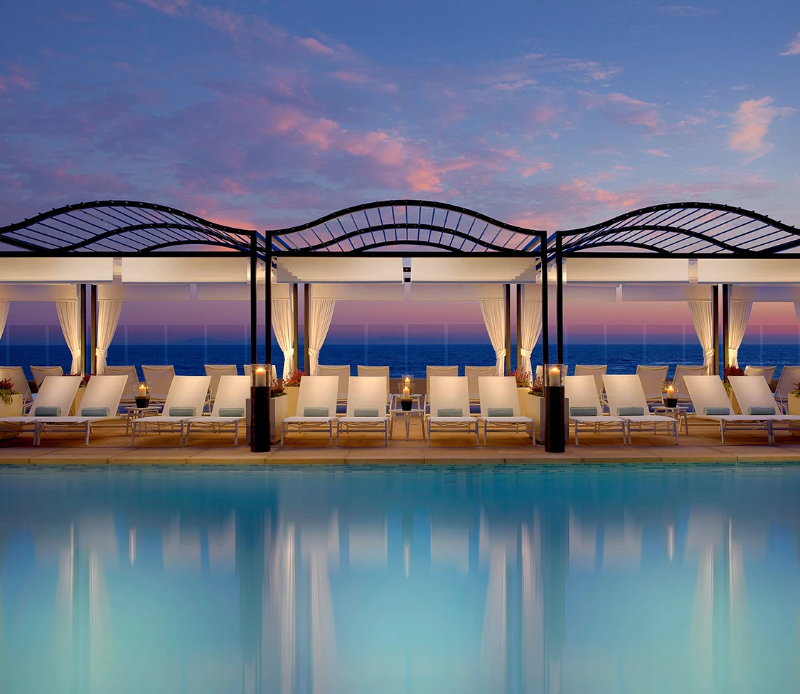 a pool with lounge chairs and a sunset