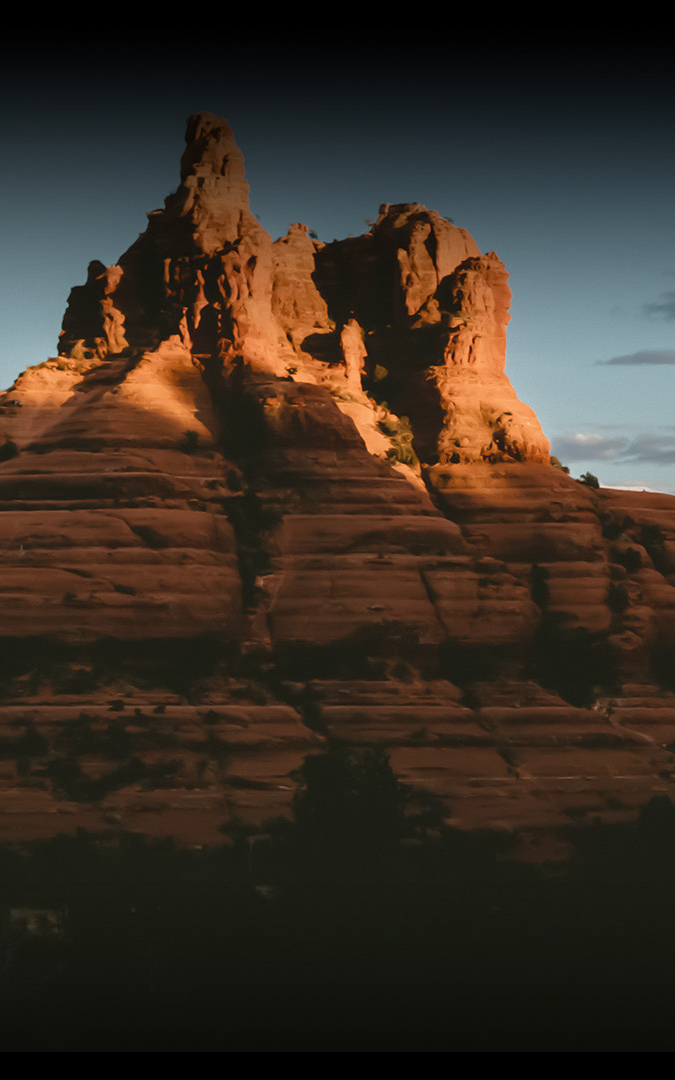 a large rock formation with trees in the background