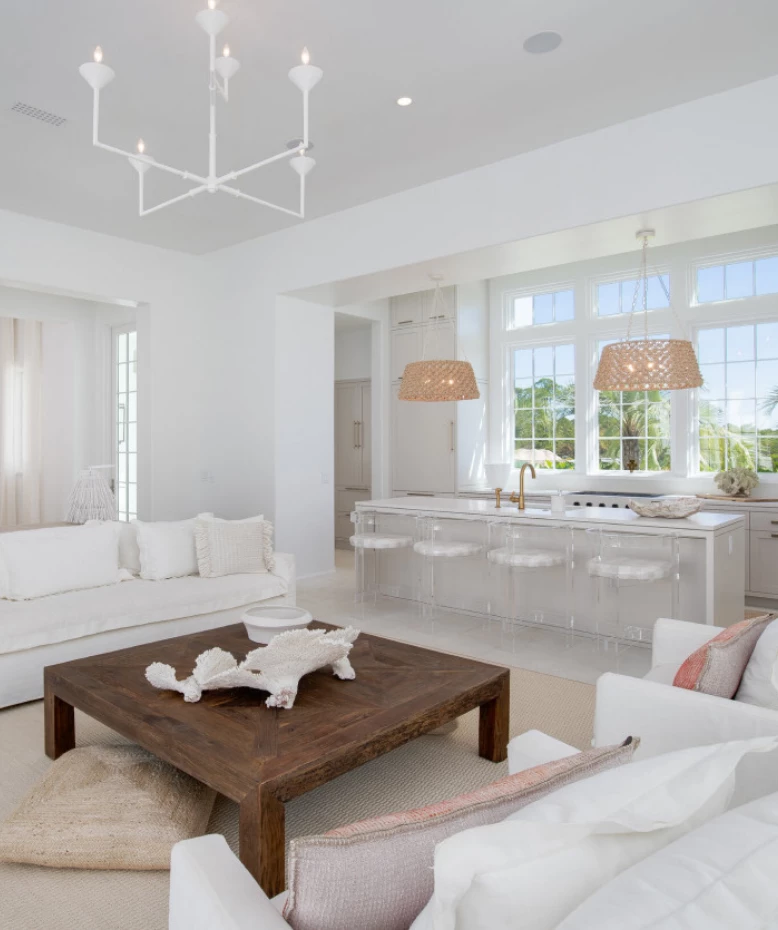 a living room with white furniture and a kitchen
