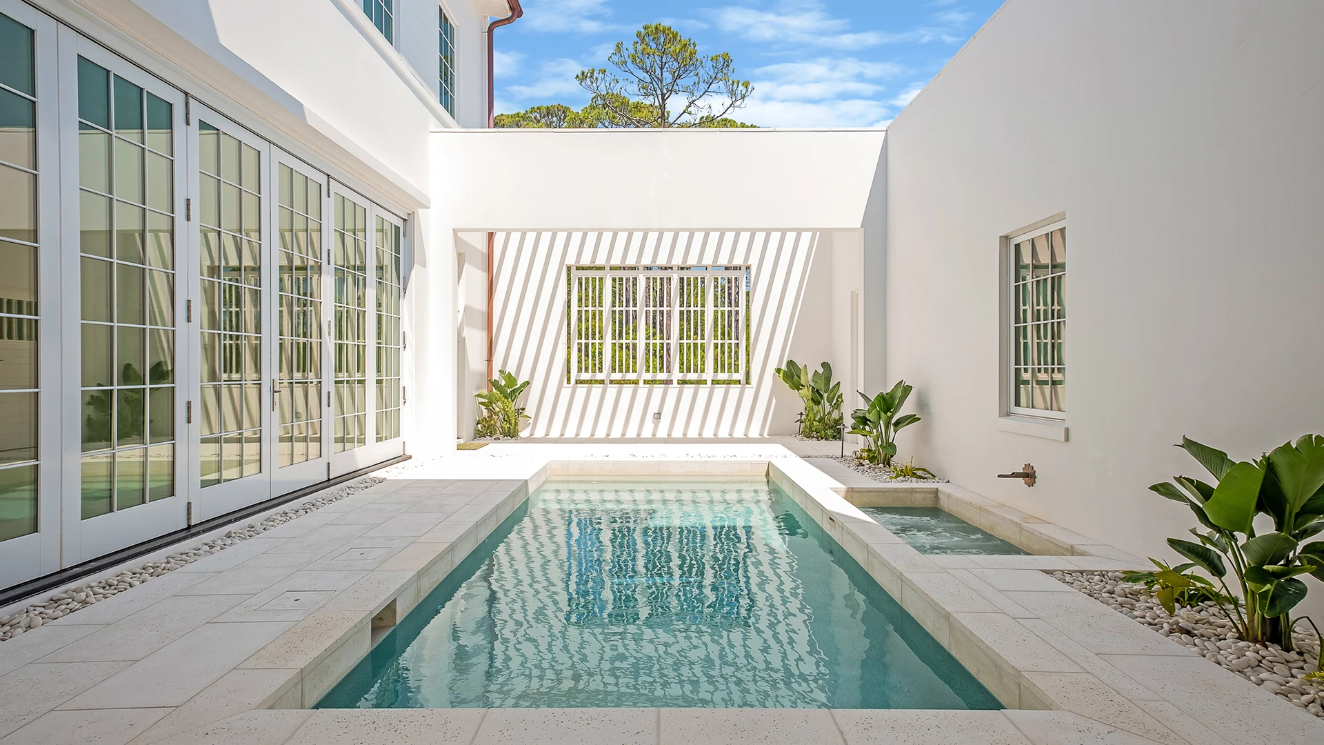 a swimming pool in a courtyard between two white buildings