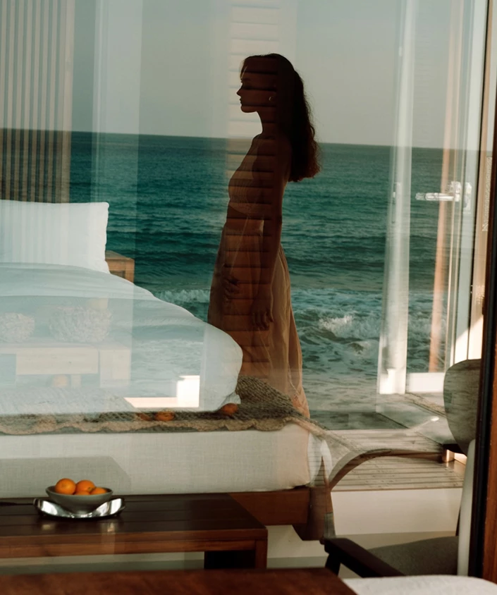 a woman standing on a bed looking out a window