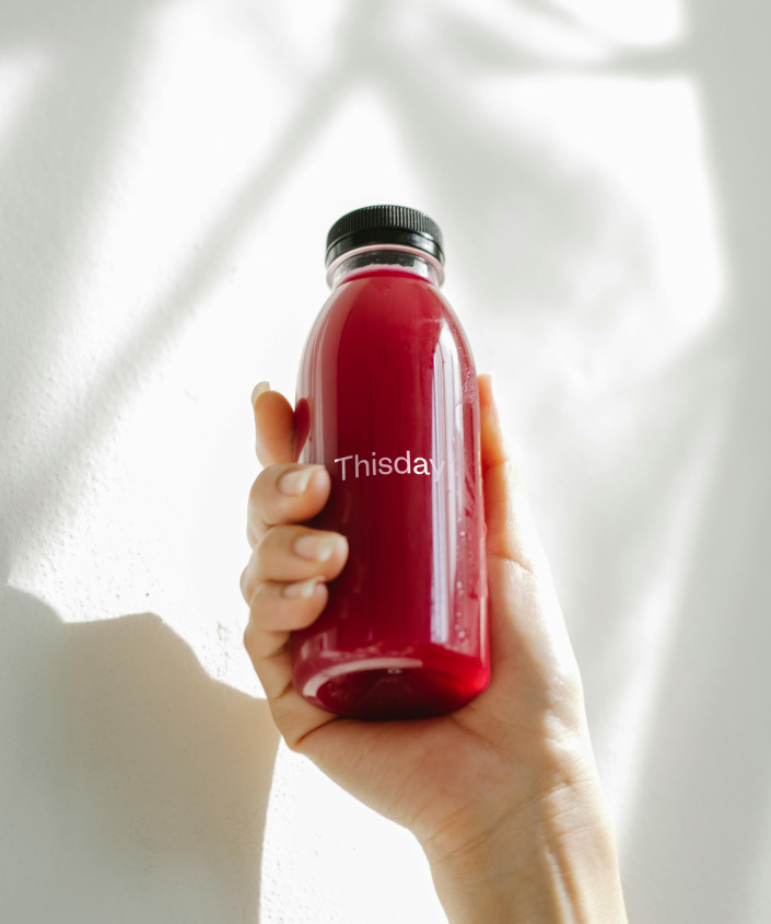 a hand holding a bottle of red liquid