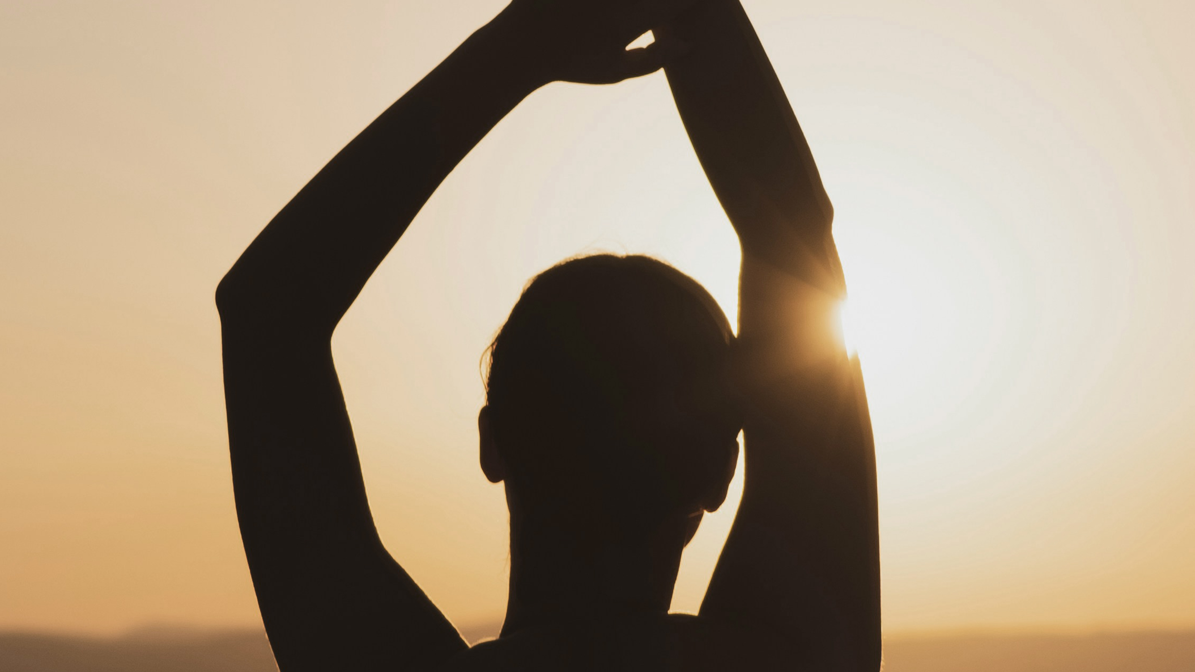 a silhouette of a woman stretching her arms