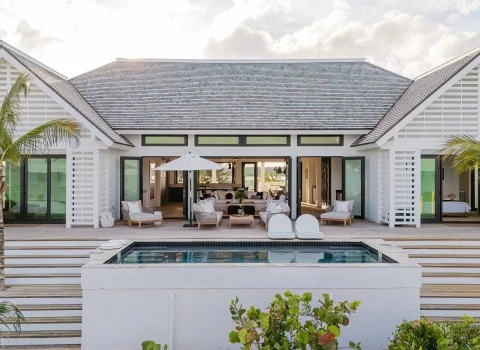 a white house with a pool and chairs