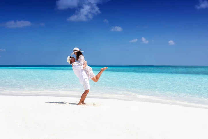 a man in a white dress on a beach