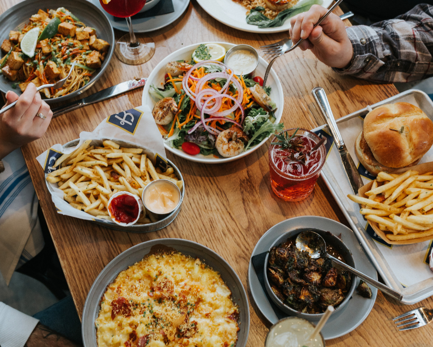 a group of people eating at a table with food
