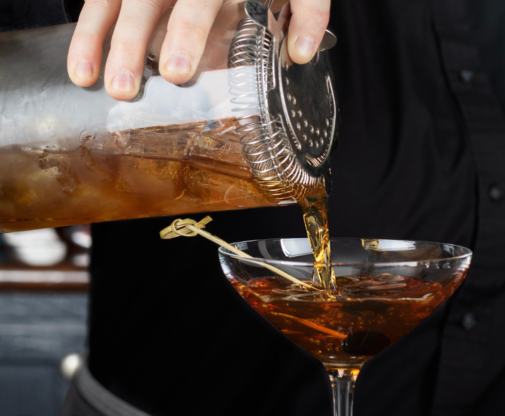 a person pouring a drink into a glass