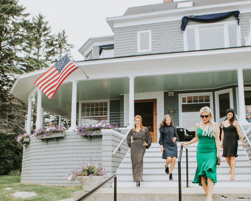 a group of women walking up stairs in front of a house