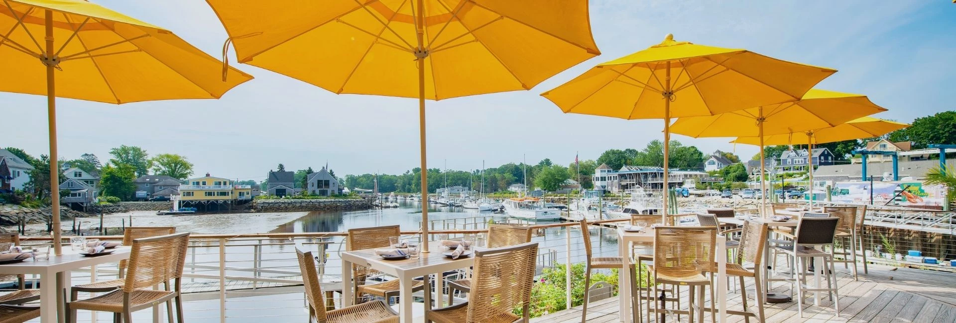 a table and chairs with umbrellas on a deck overlooking a body of water