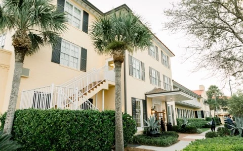 exterior shot of pale yellow hotel building with dark green shutters 