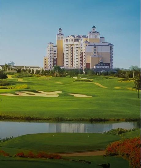 View of a golf course, small lake and a big building at the back