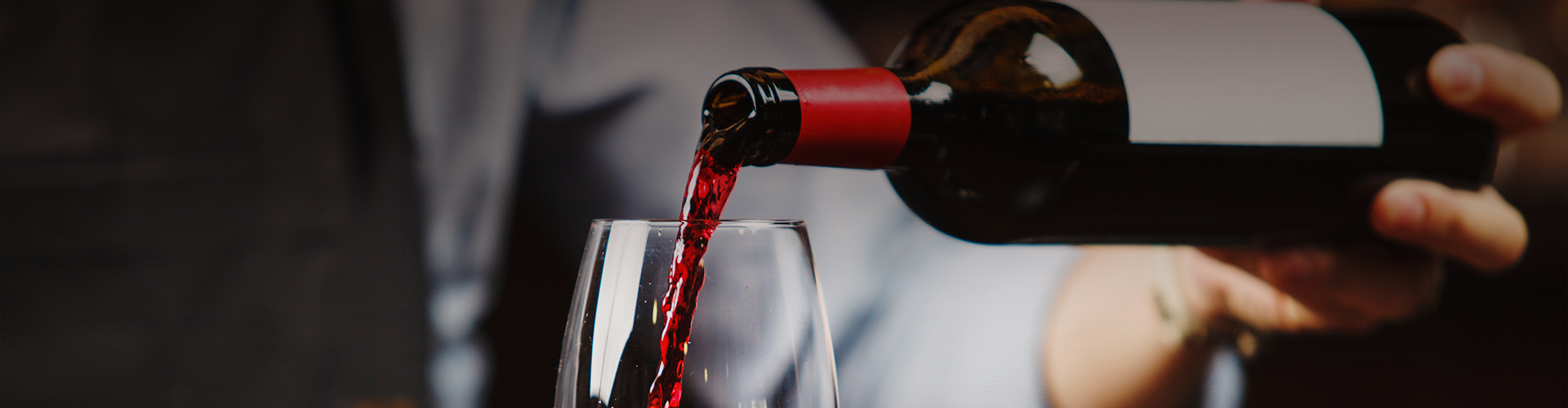 Closeup view of a hand filling a glass of red wine