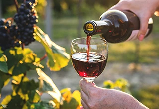 Hand filling a glass of red wine