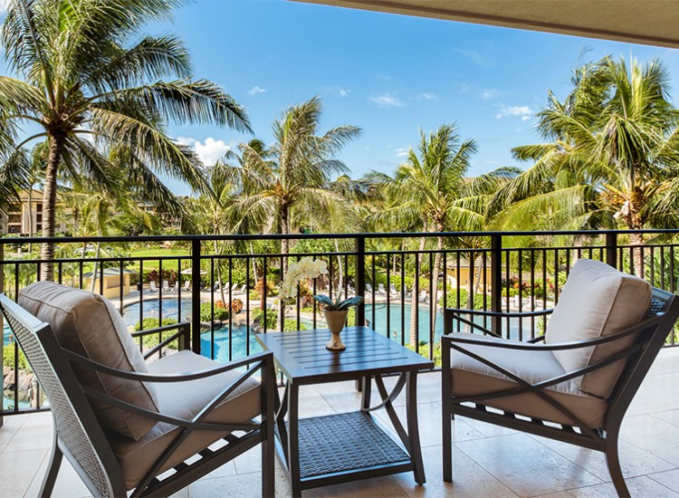 a patio with chairs and a table and a pool in the background