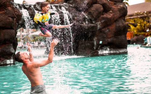 a man and a child jumping into a pool