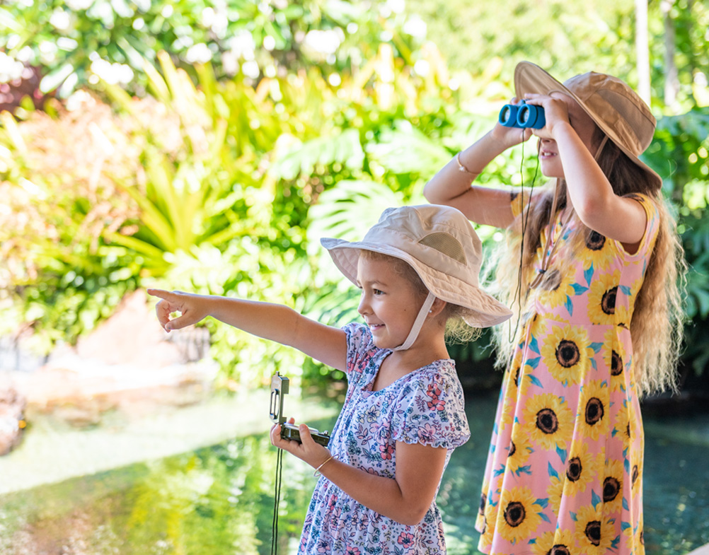two girls wearing hats and looking through binoculars