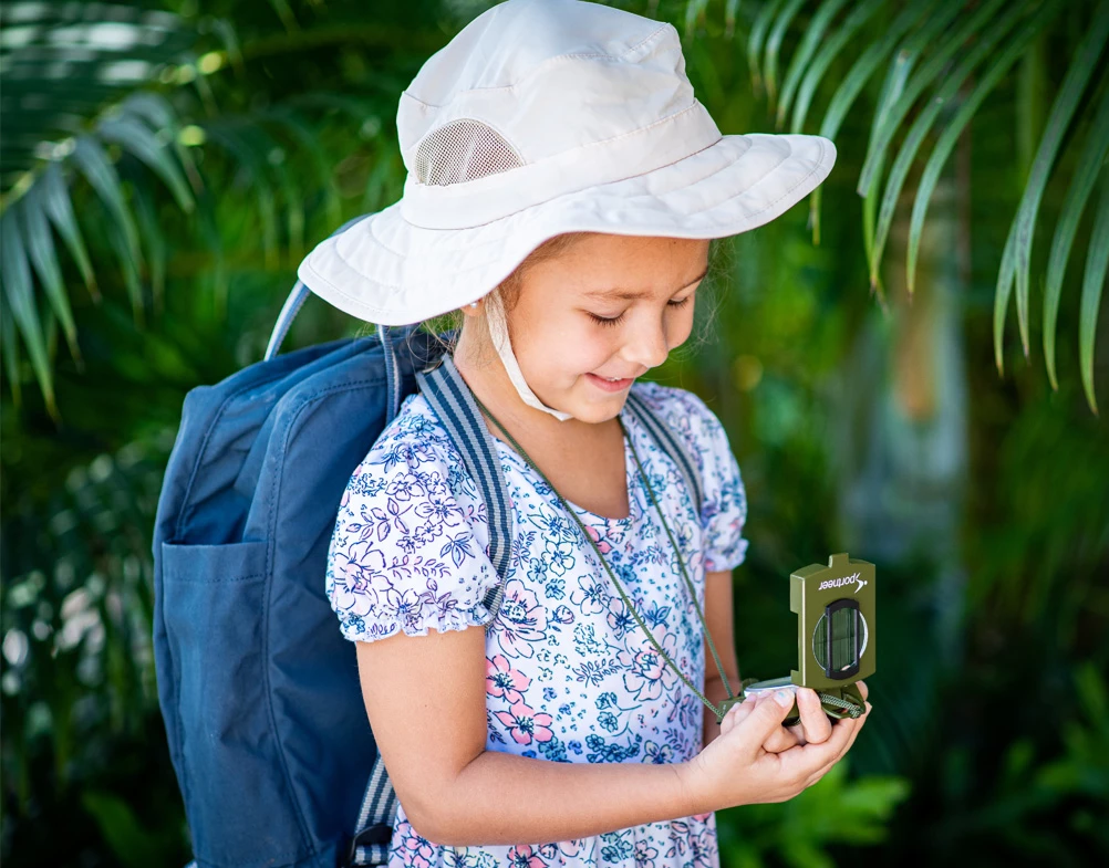 a girl wearing a hat and holding a small device