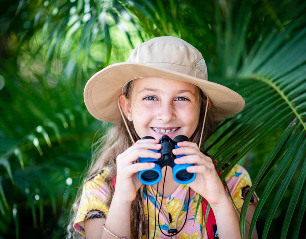 a girl wearing a hat and holding binoculars