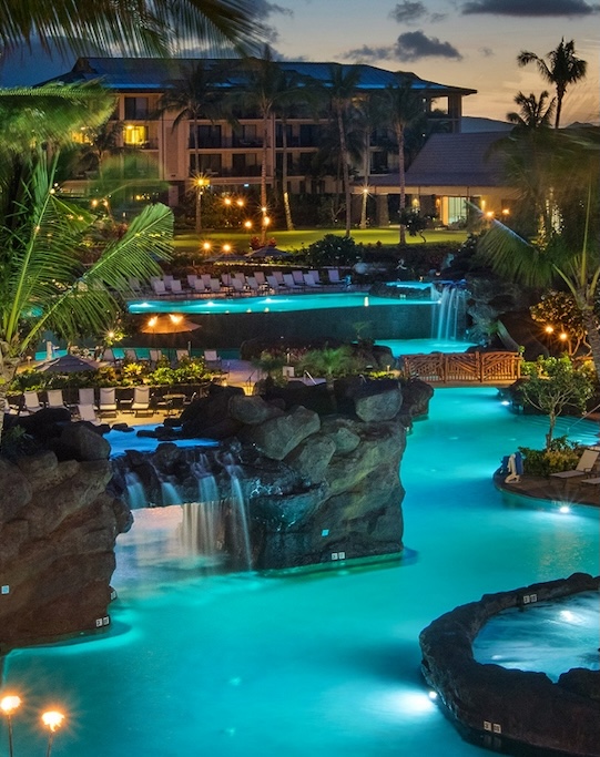 a pool with a waterfall and a hotel