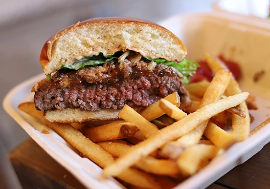 a burger and fries in a styrofoam container