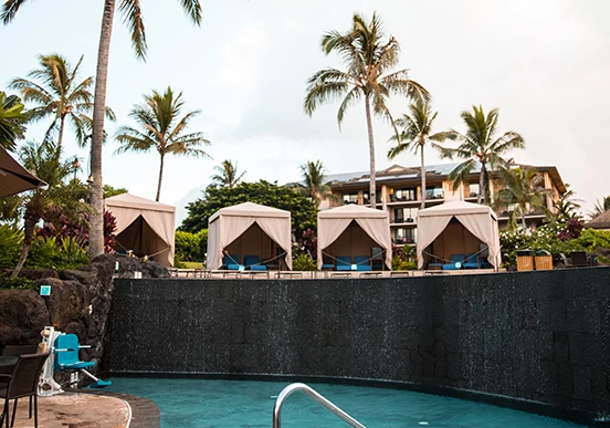 a pool with a group of chairs and cabanas