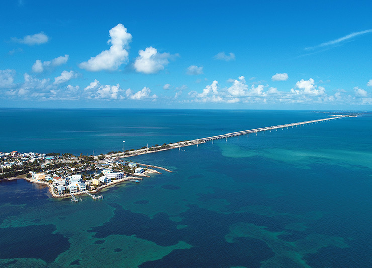 a drone shot of the island with a long bridge