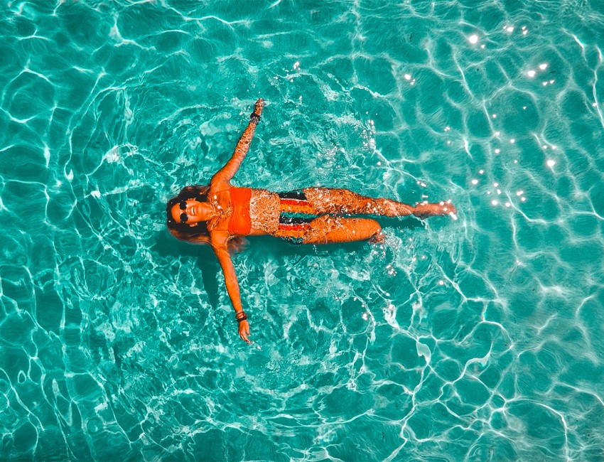 a woman floating in the water while wearing sunglasses as the sun is shining