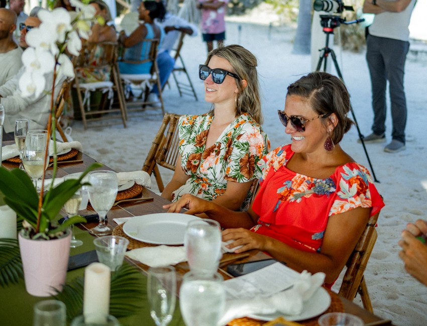 a couple of women sitting at a table with food and drinks