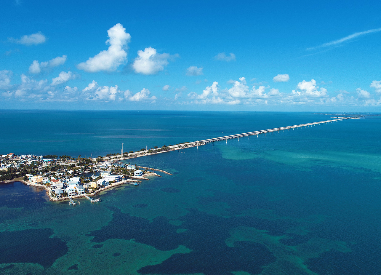 aerial view of the ocean and a long bridge
