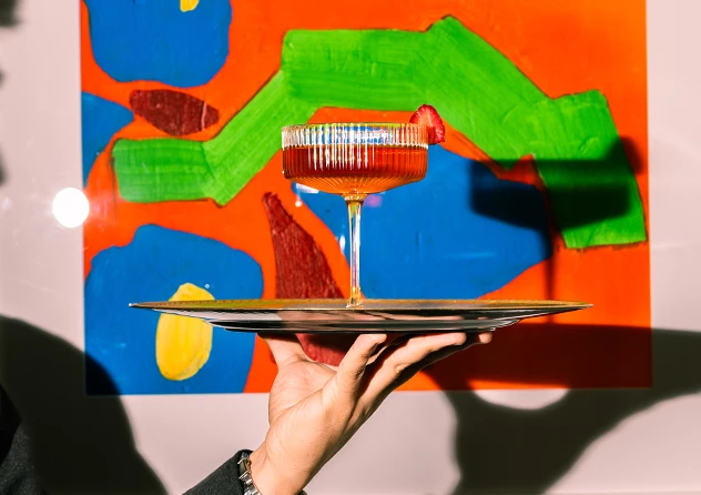 a hand holding a tray with a drink on it